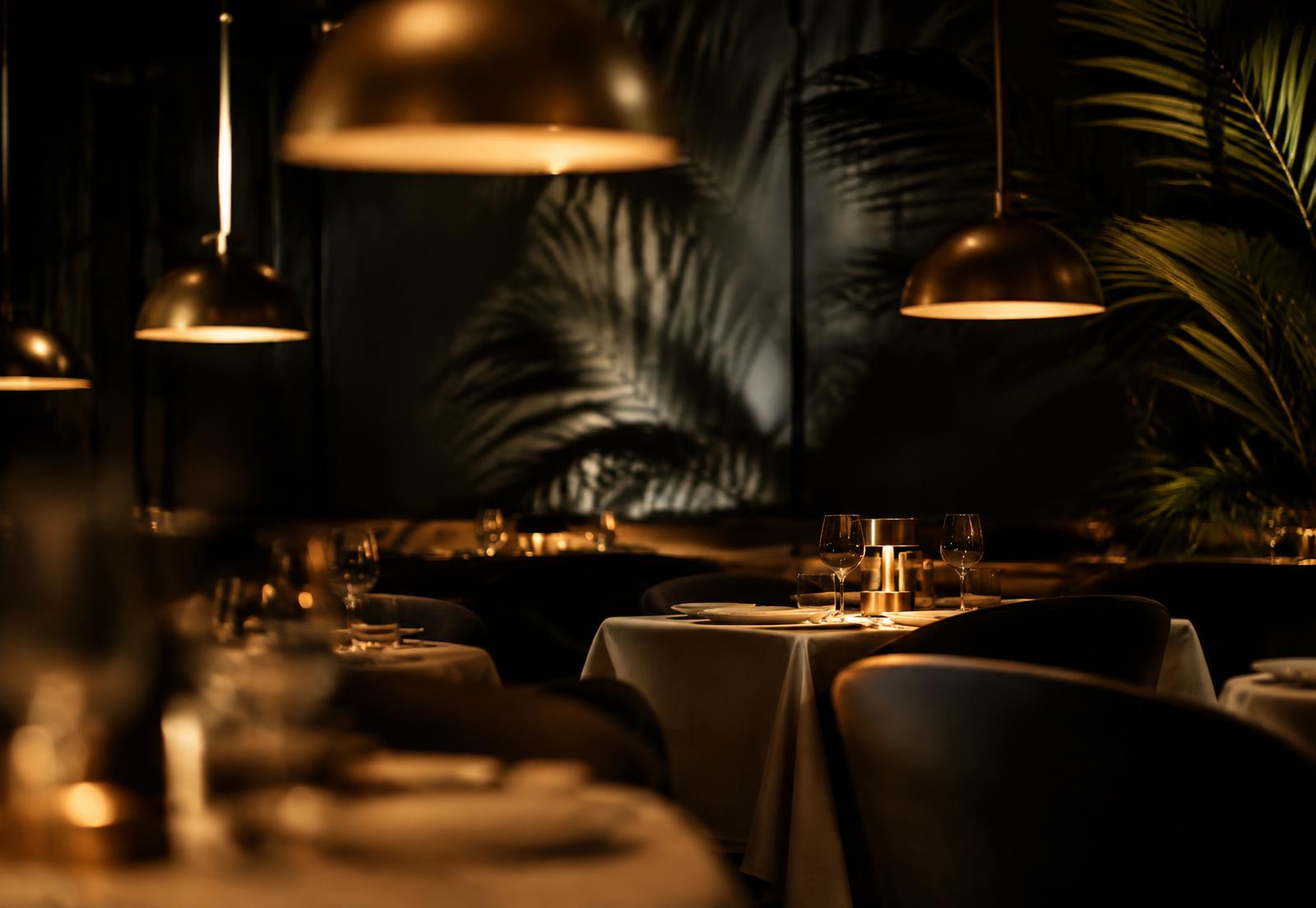 Conceptual dining room atmosphere with brass pendant lights and palm shadows